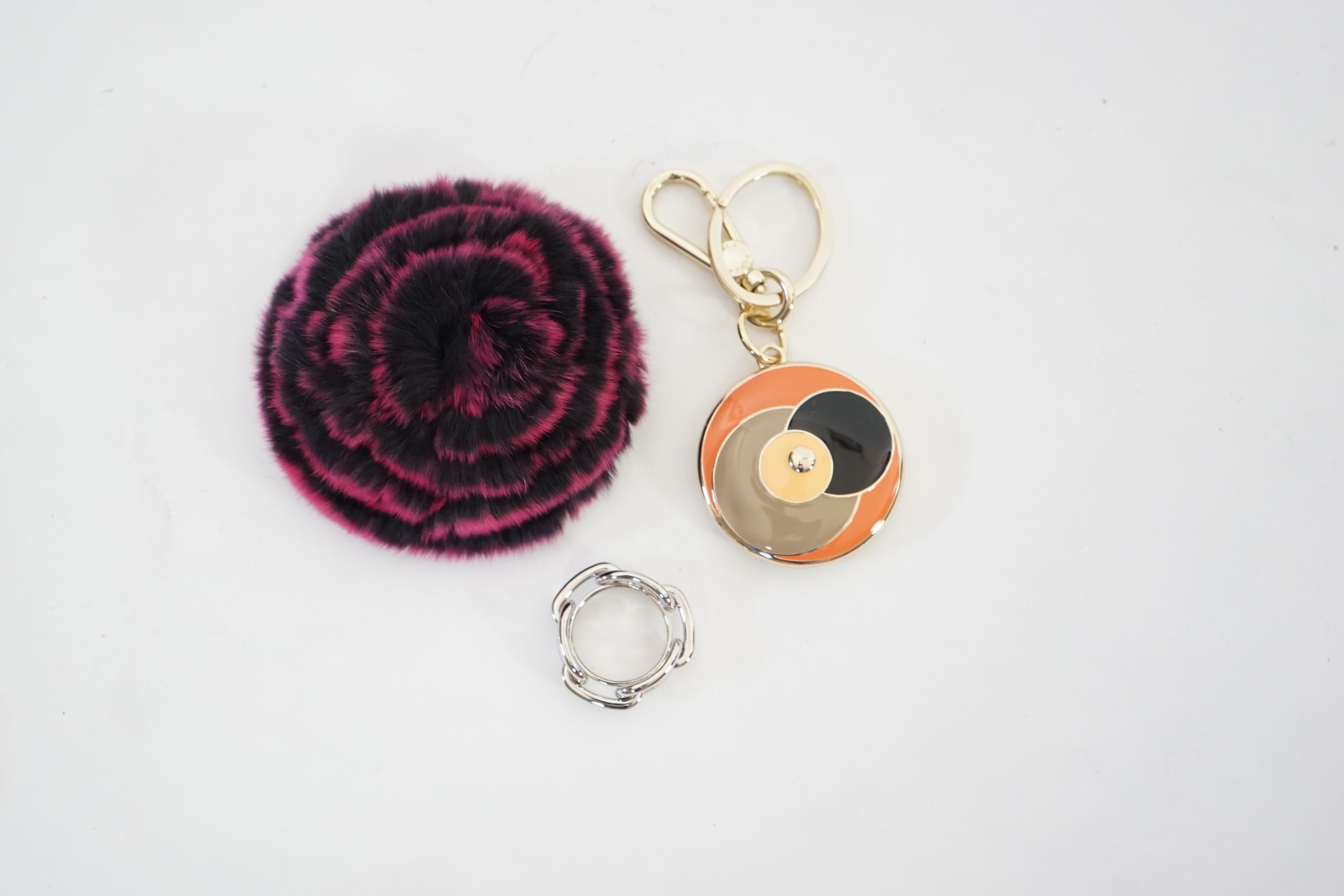 A boxed Hermes scarf ring, with box and bag and a Furla key ring and fur brooch.